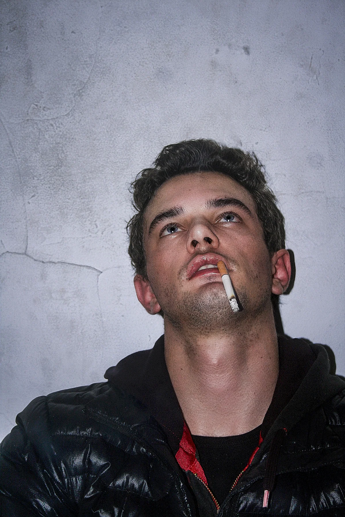 Portrait with a cigarette against a grey wall